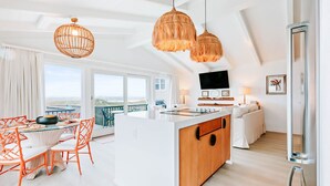 Une cuisine moderne dotée d’un îlot central, de grandes fenêtres et d’un balcon avec un espace salon extérieur.