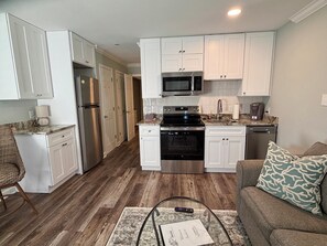 A compact kitchen with white cabinets, stainless steel appliances, and a marble countertop. - SunnyDaze-Brand new reno- King bed, Free bikes! (Hilton Head Island)