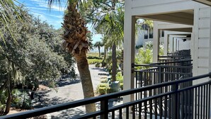 A view from a balcony overlooking a landscaped area with palm trees and a road. - SunnyDaze-Brand new reno- King bed, Free bikes! (Hilton Head Island)