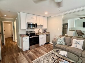 A modern kitchen with white cabinetry, stainless steel appliances, and a wooden floor. - SunnyDaze-Brand new reno- King bed, Free bikes! (Hilton Head Island)