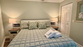 Un dormitorio con una cama, dos lámparas de noche, un ventilador de techo y una puerta.