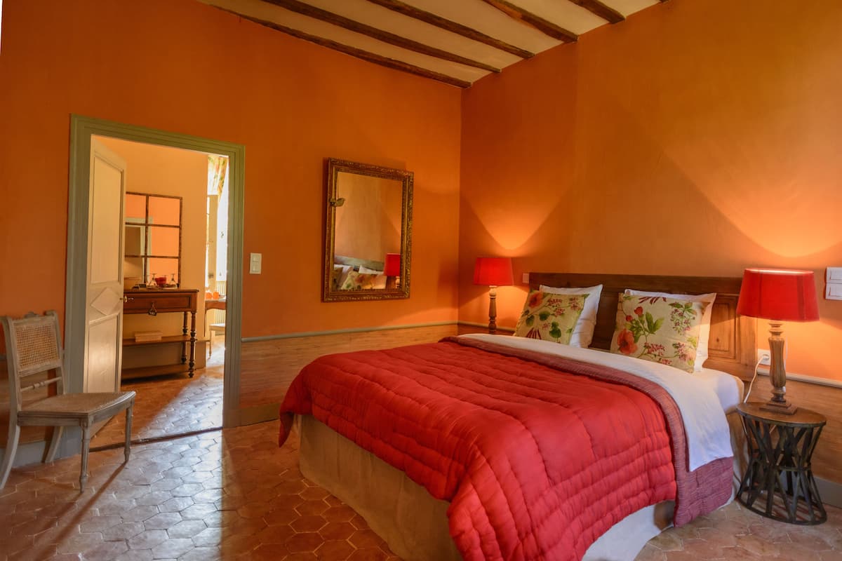 Un dormitorio con una cama grande, un cabecero de madera, dos lámparas de noche y un espejo en la pared.