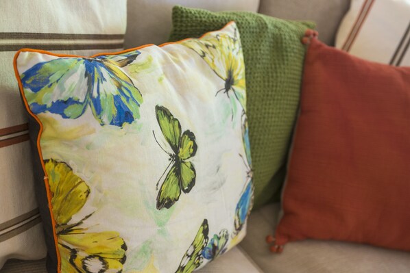Un gros plan d’un coussin à motifs floraux orné d’un motif de papillon, posé sur un canapé.