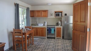 A compact kitchen with wooden cabinets, a microwave, a refrigerator, and a stove.