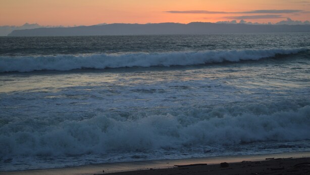 A beach with waves at sunset.