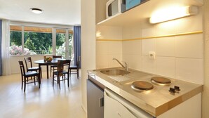 A modern kitchen with a built-in dishwasher, a sink, and a dining area with a table and chairs. - Vacancéole - Le Domaine de Chames (Vallon-Pont-d'Arc)