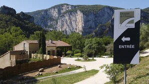 A sign indicating the entrance to Domaine de Chames with a view of a mountain and a building with a tiled roof. - Vacancéole - Le Domaine de Chames (Vallon-Pont-d'Arc)