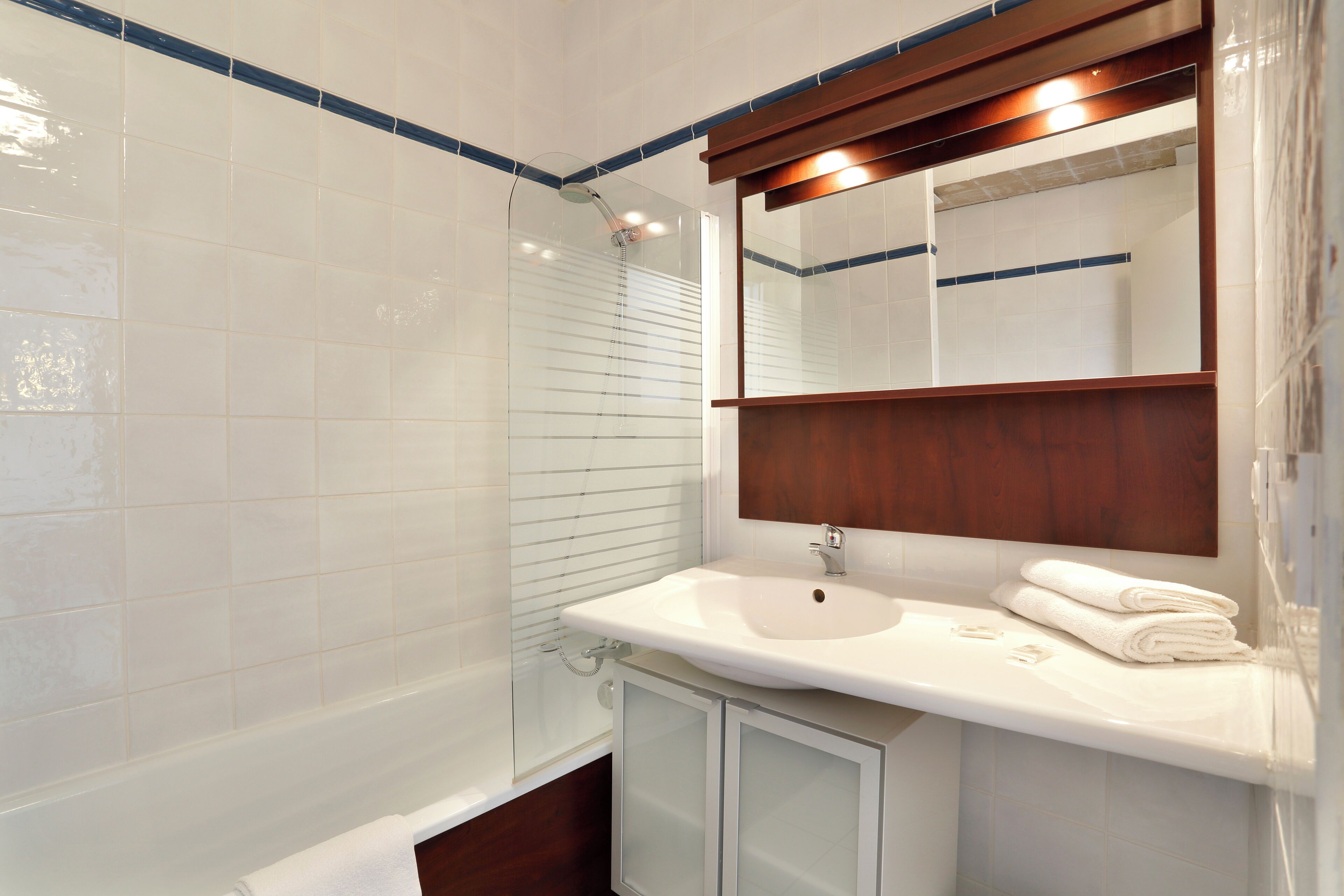 Un baño con lavamanos blanco, espejo y cabina de ducha de vidrio.