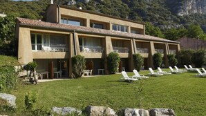 A two-story building with a flat roof, multiple balconies, and a well-maintained lawn with sun loungers. - Vacancéole - Le Domaine de Chames (Vallon-Pont-d'Arc)