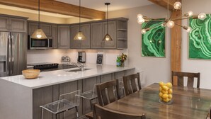 A modern kitchen with wooden beams, stainless steel appliances, and a central island with chairs.