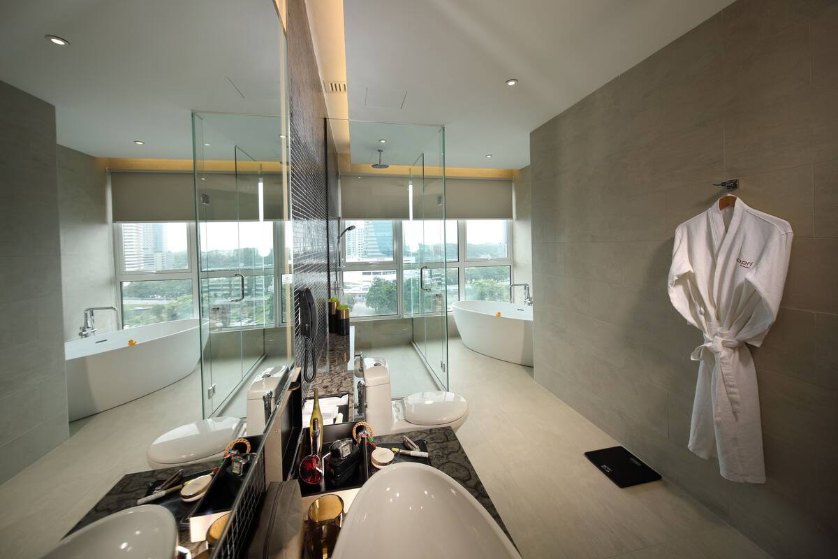 Une salle de bain moderne dotée d’une grande baignoire, d’une douche à parois de verre et offrant une vue sur la ville.
