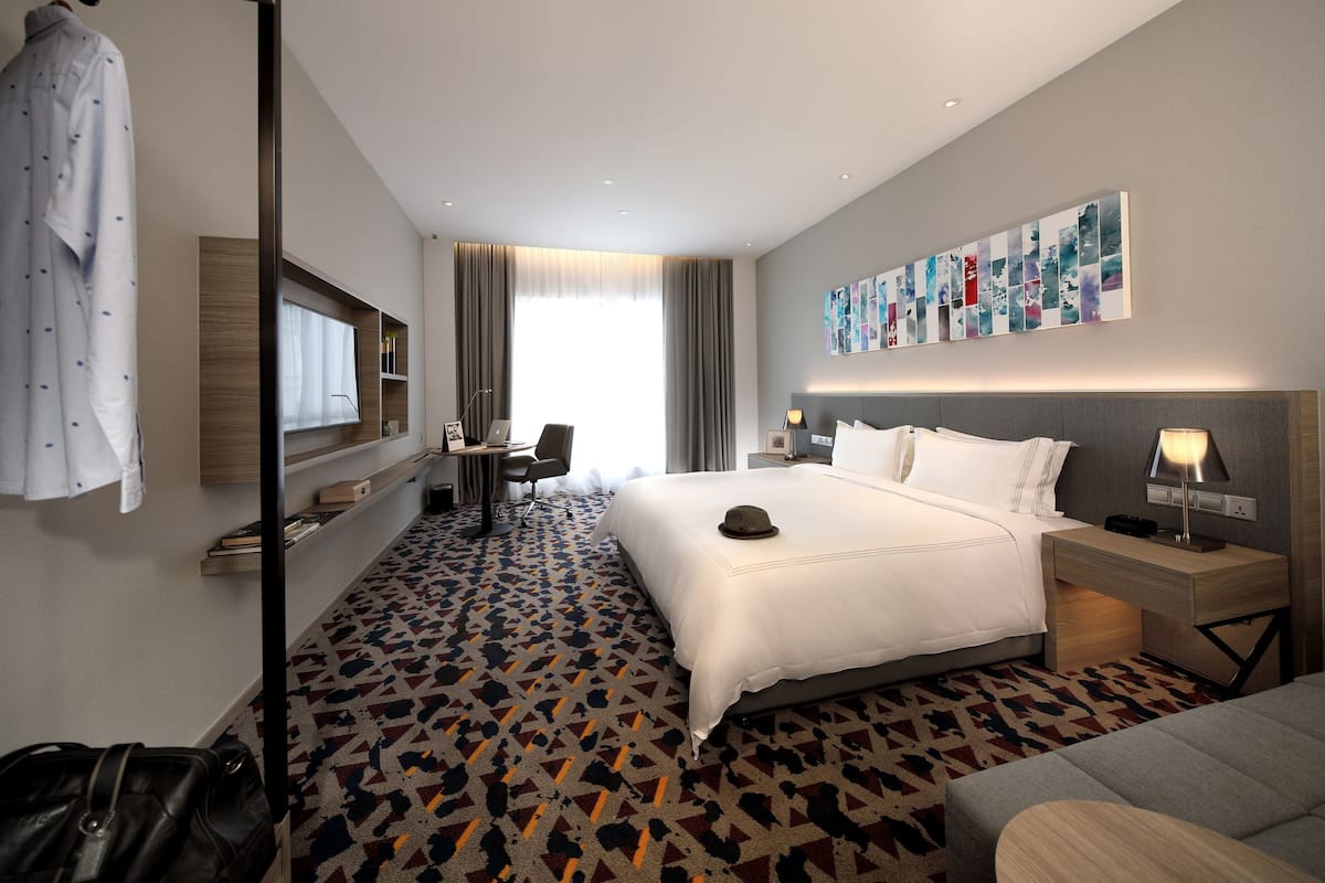 Une chambre d’hôtel avec un grand lit, un bureau avec une chaise, une télévision et un mur décoré d’un collage de photos.