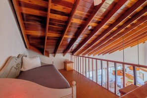 A bedroom with a wooden ceiling, a bed, a nightstand, and a view of the outside through large windows. - Newly Remodeled Three Bedroom Beachfront Condominium at The Landings (San Pedro)