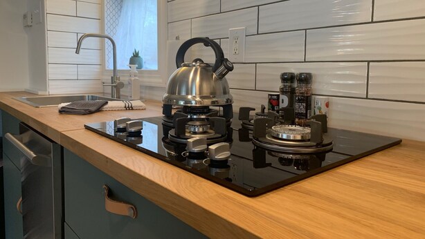A modern kitchen with a black induction cooktop, a kettle, and a sink.