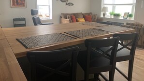 A spacious dining area with a long wooden table, multiple chairs, and decorative rugs.