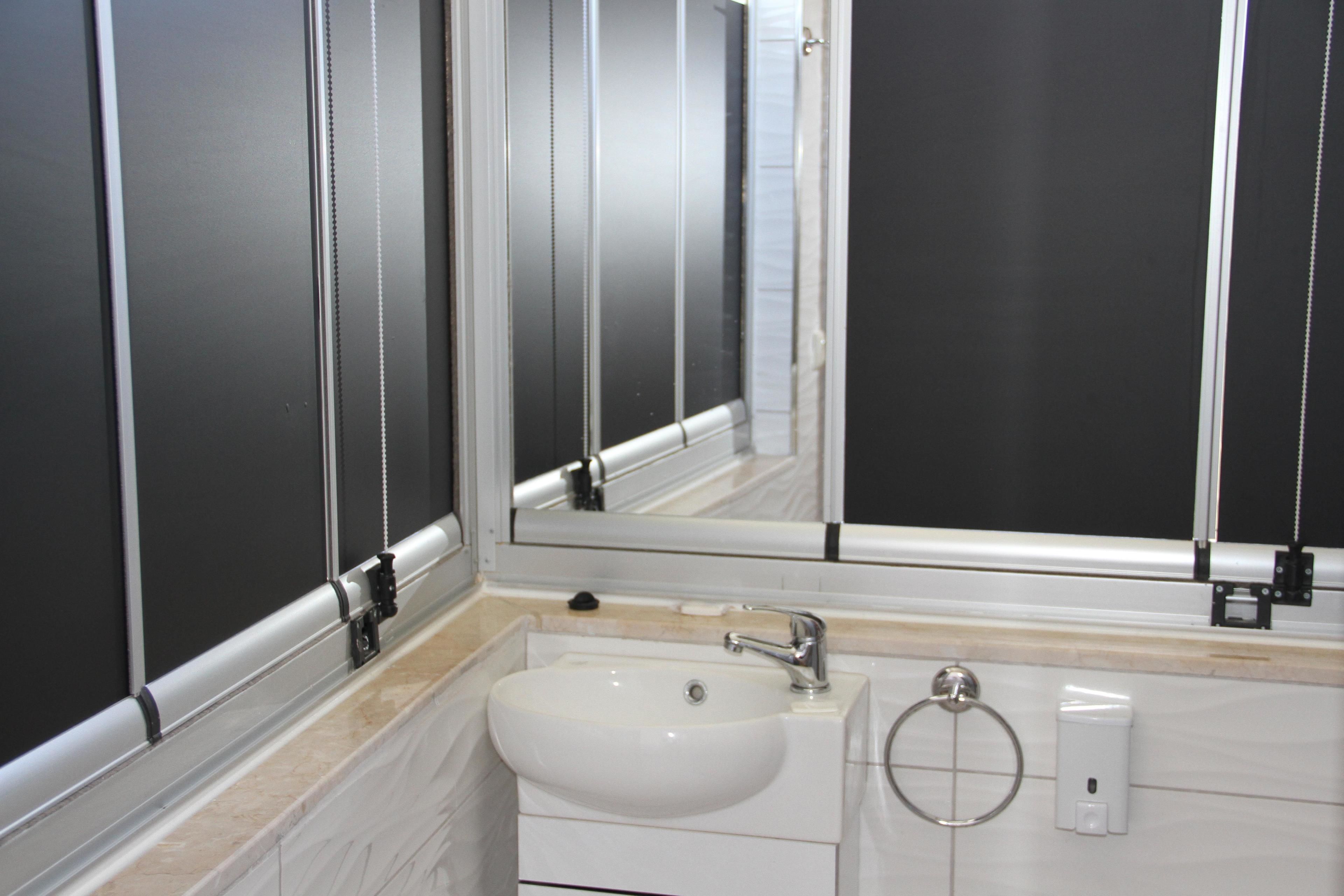Un baño moderno con lavamanos blanco, un espejo y un aro para toallas.