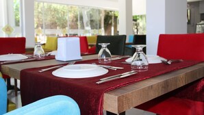Comedor con mesa de madera para cuatro personas, sillas rojas y mantel rojo.