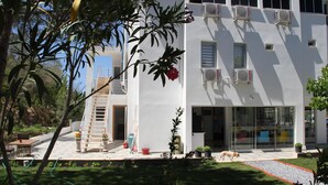 Un edificio moderno con fachada blanca, múltiples unidades de aire acondicionado y una entrada de vidrio.