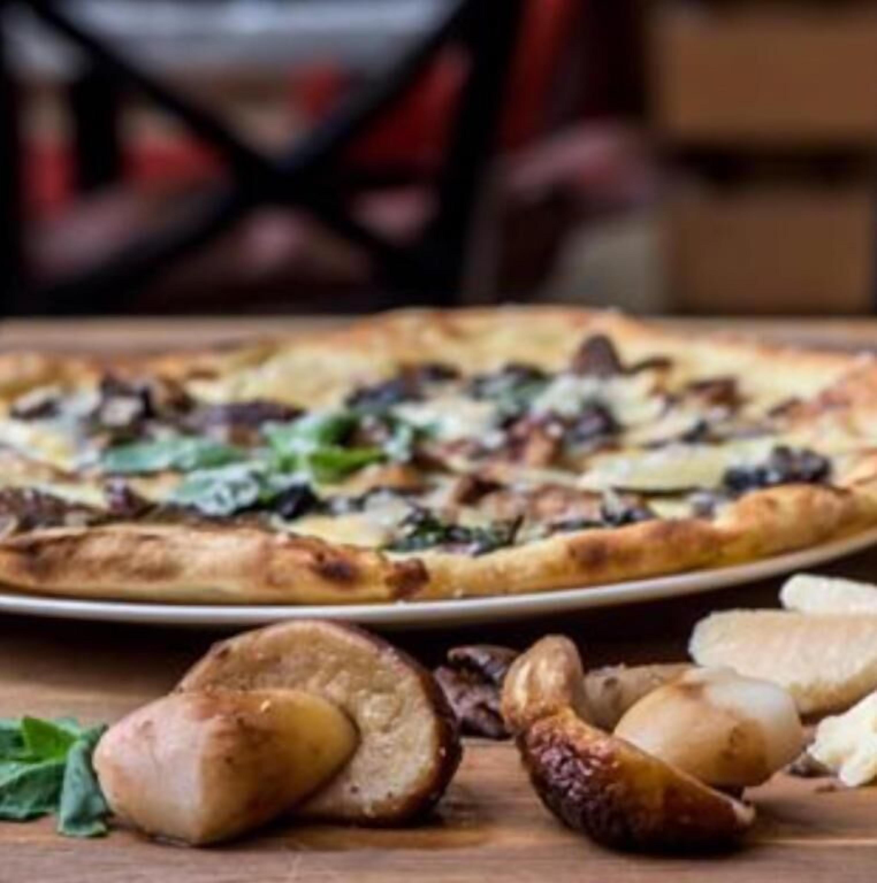 Una pizza con diversi condimenti su un tavolo di legno.