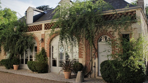 A building with a brick facade, arched windows, and a covered entrance. - Les Rives de la Tronne (Mer)