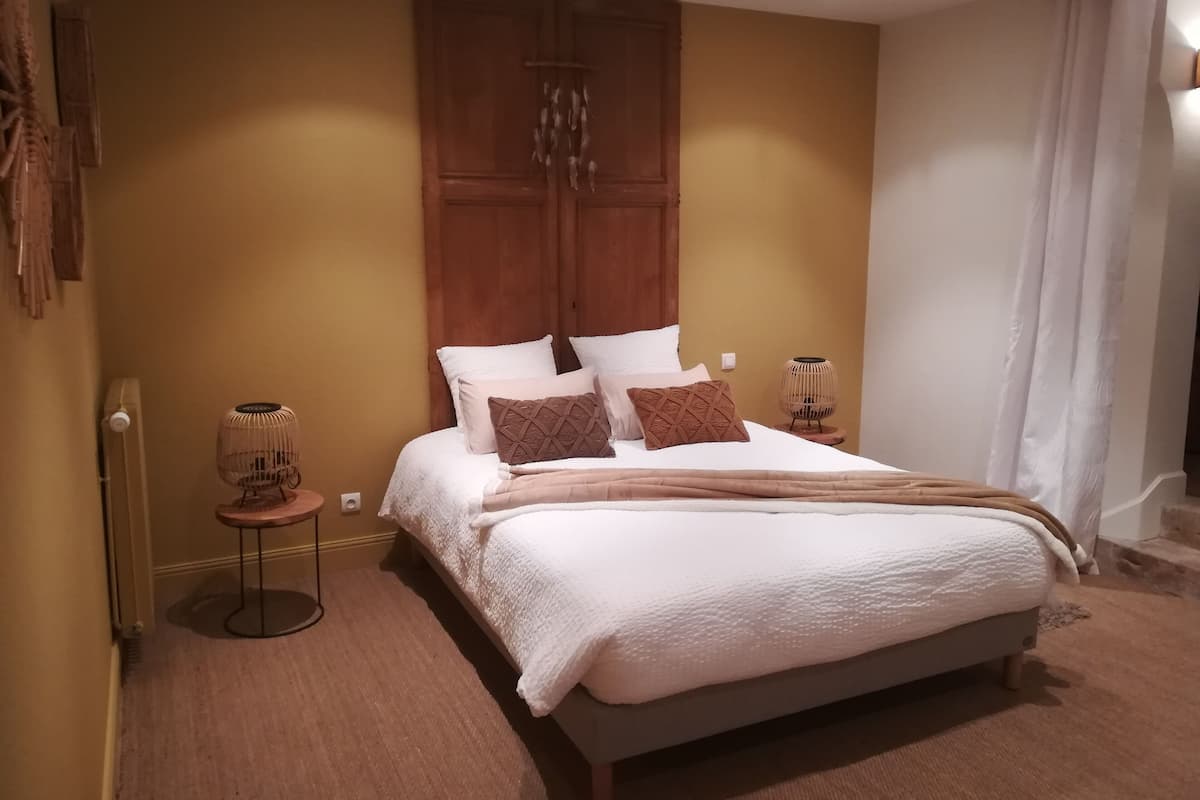 A bedroom with a large bed, a wooden wardrobe, a bedside table with a lamp, and a radiator.