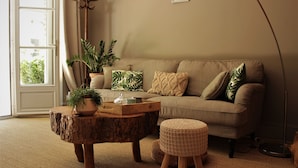A cozy living room with a sofa, a coffee table, and a floor lamp. - Les Rives de la Tronne (Mer)