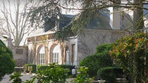 A courtyard with a building featuring arched windows and a stone facade. - Les Rives de la Tronne (Mer)