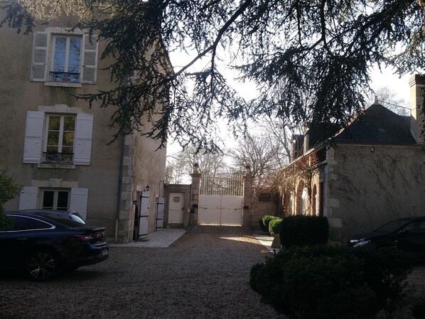 A narrow street with buildings on either side, a gravel path, and parked cars.