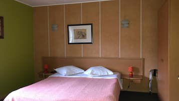 Quarto de hotel com uma cama, duas mesas de cabeceira, um criado-mudo, uma moldura na parede e um guarda-roupa.