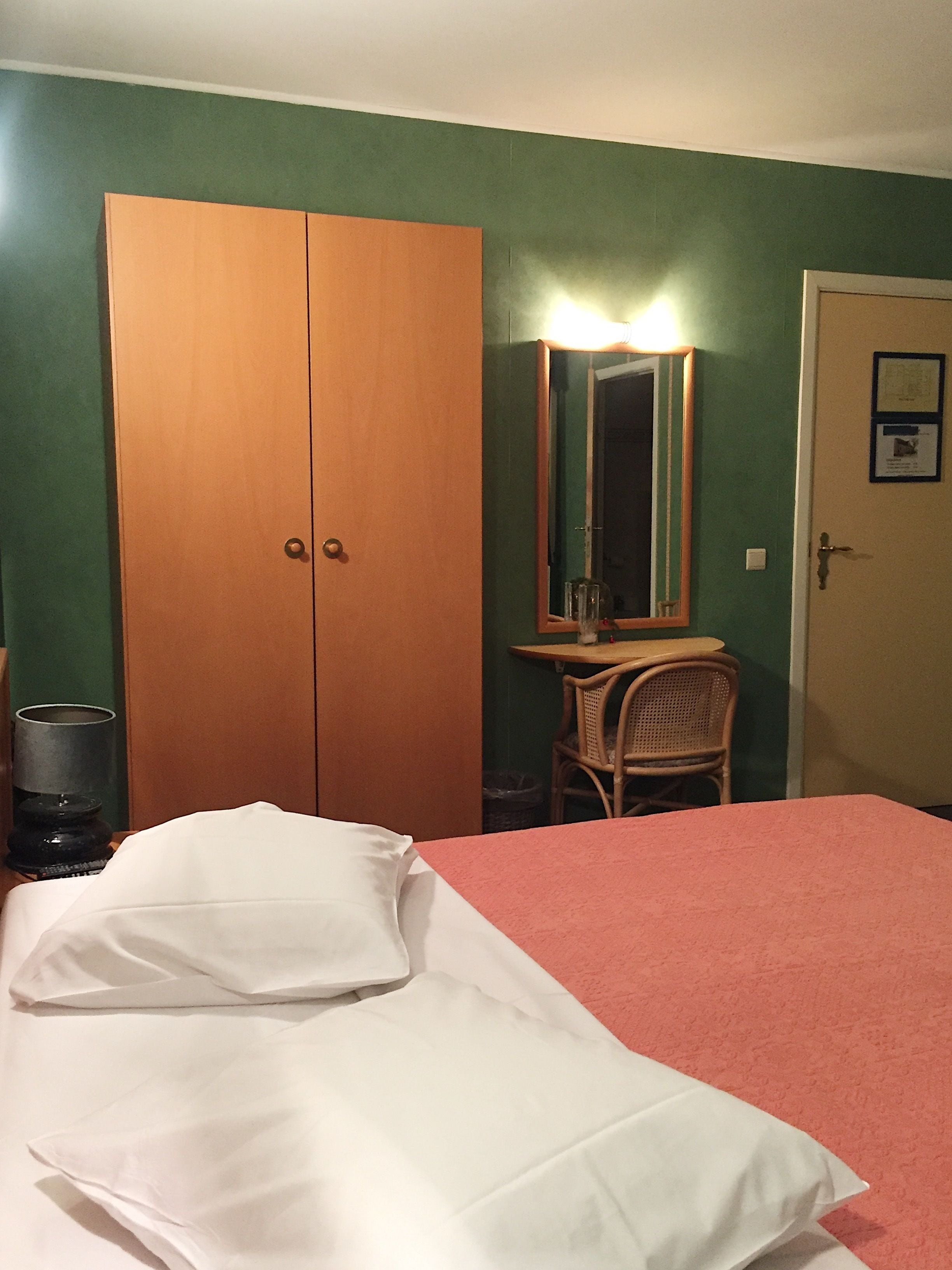 Una habitación con cama, armario, silla y mesa.