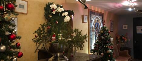 A warmly lit living room with a Christmas tree, a large decorative bowl, and a fireplace.