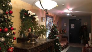 A warmly lit living room with a Christmas tree, a fireplace, and a dining area. - Hotel In den Hoek (Tielt-Winge)