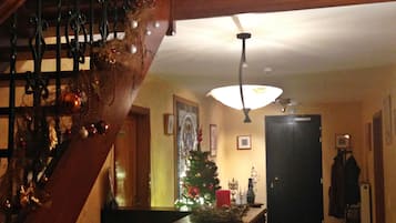 Una scala con ringhiera addobbata con decorazioni natalizie che conduce a una stanza con un albero di Natale e un tavolo con una candela.