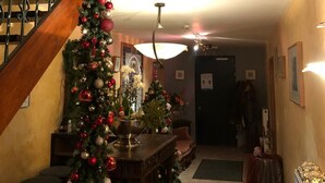 A staircase with a Christmas tree decorated with red and white ornaments, leading to a second-floor landing with a wreath. - Hotel In den Hoek (Tielt-Winge)