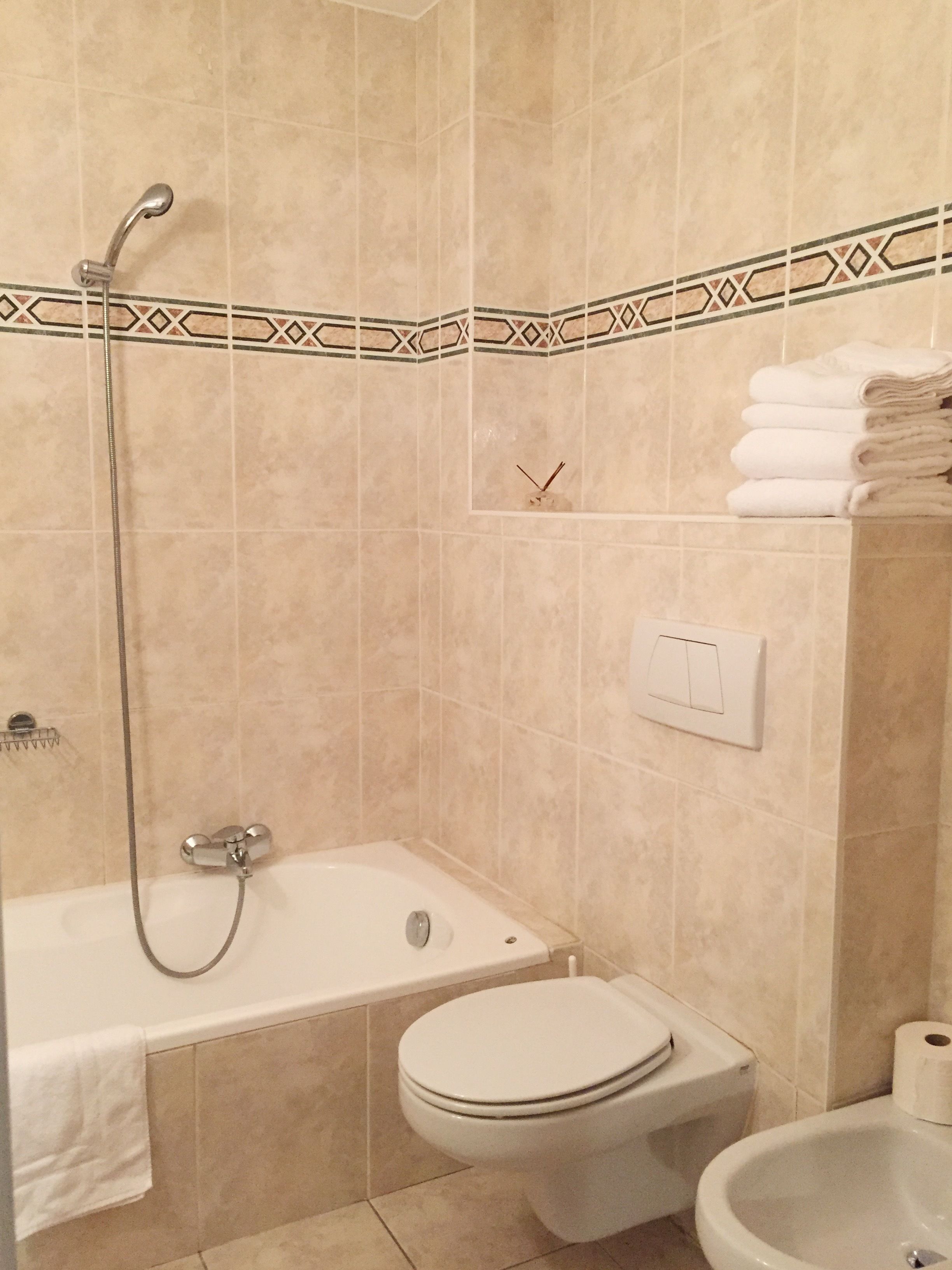 Une salle de bain équipée d’une baignoire, de toilettes, d’un bidet et d’un porte-serviettes.