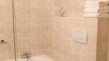 Une salle de bain équipée d’une baignoire, de toilettes, d’un bidet et d’un porte-serviettes.
