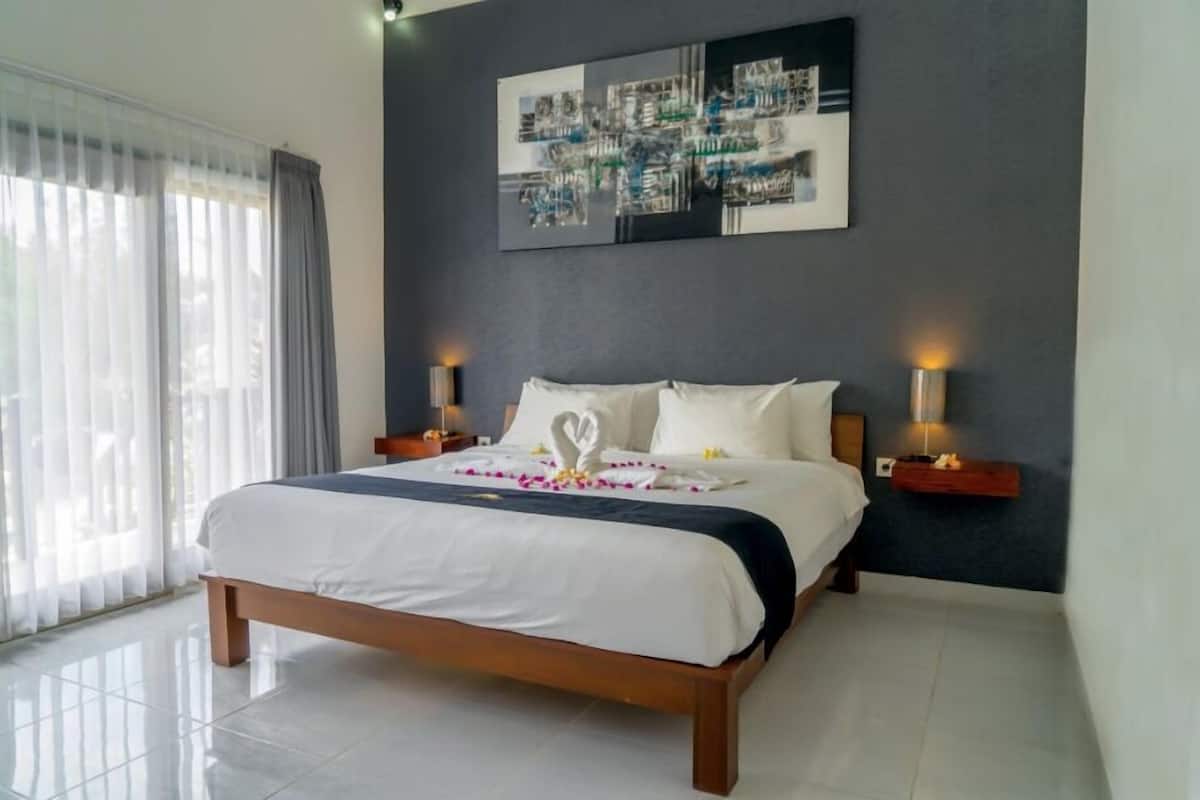 A neatly made bed with a heart-shaped decoration, a wall art piece, and two bedside lamps.