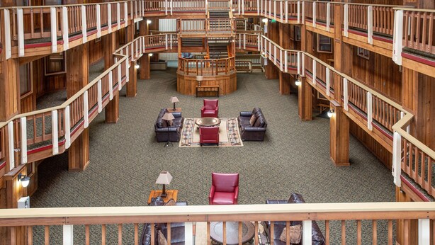 A multi-level wooden interior with a central seating area, multiple balconies, and a spiral staircase.