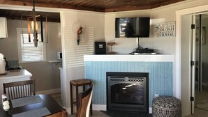 Eine gemütliche Küche mit Kamin, Holzboden und einem Essbereich mit Tisch und Stühlen.