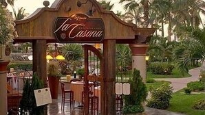 A wooden entrance archway with the name "La Casona" and a sign indicating a restaurant. - Villa 2206 2BR/3BA Ground Level Condo at Villa La Estancia on Medano Beach (Cabo San Lucas)