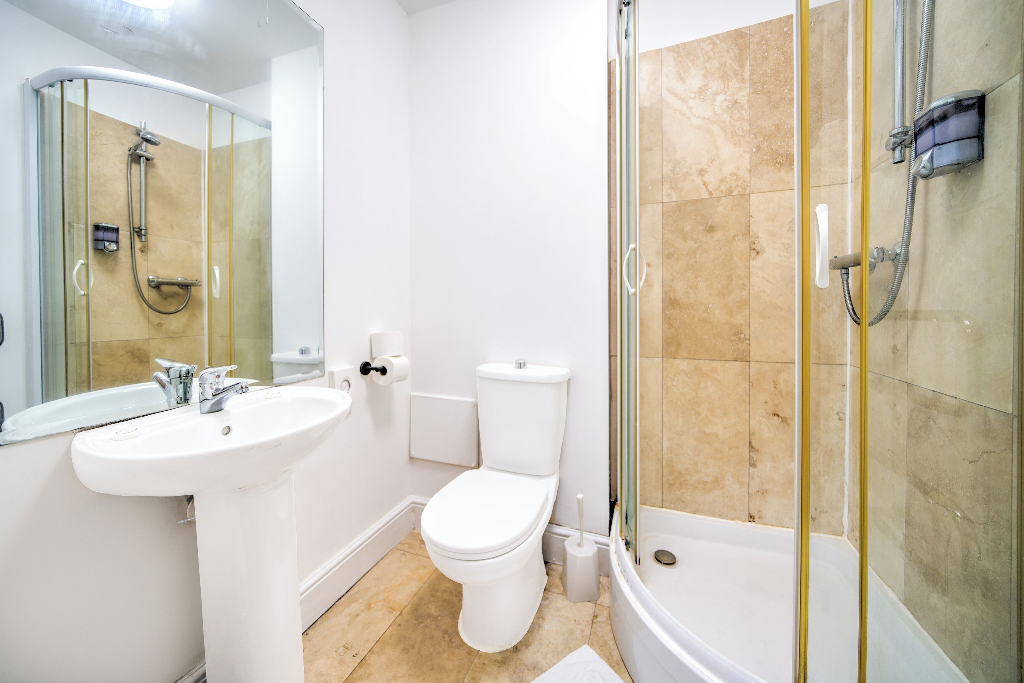 Un baño moderno con ducha de vidrio, lavamanos blanco y retrete.