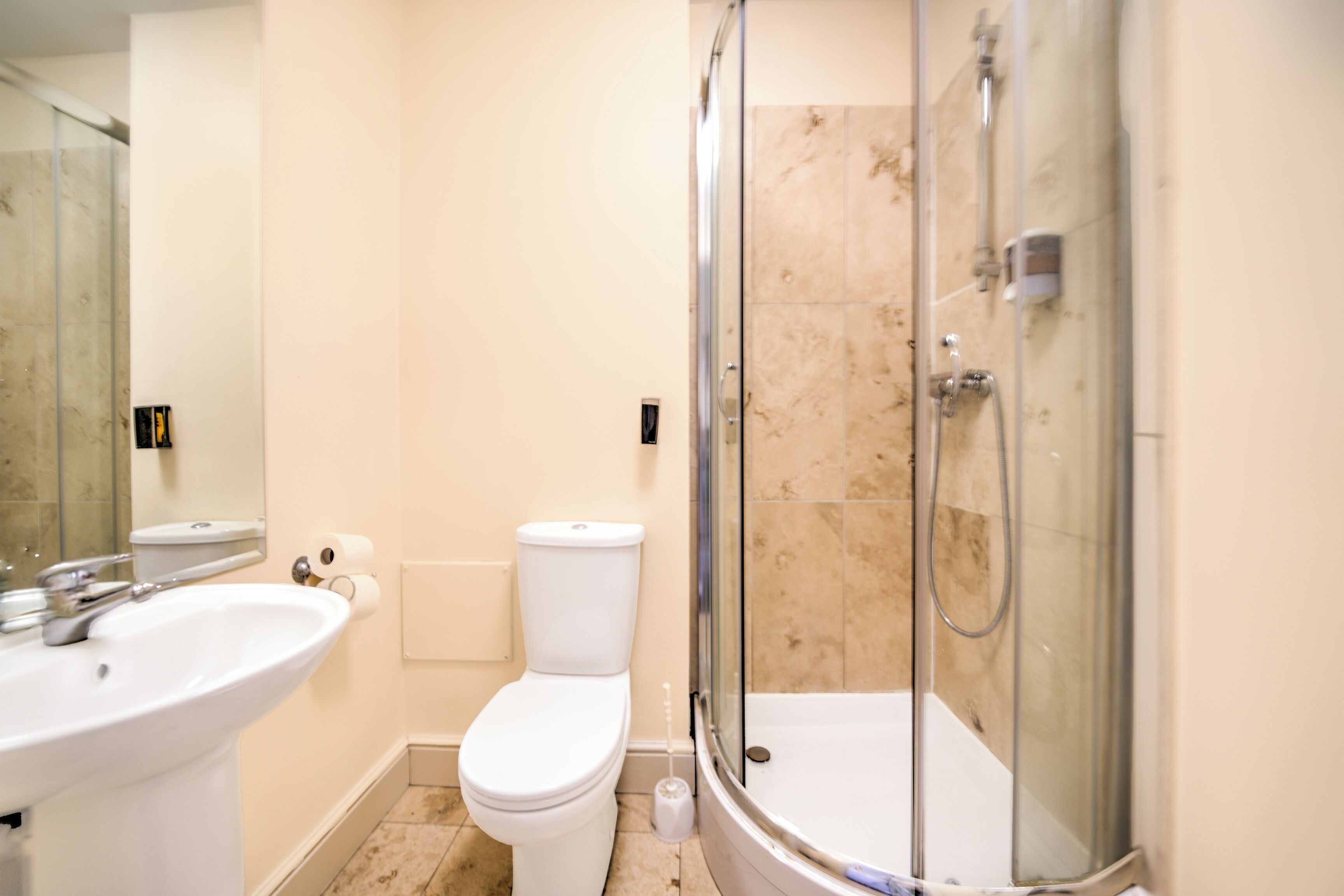 A bathroom with a sink, toilet, and glass-enclosed shower.