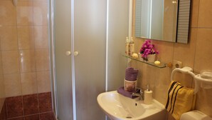 A bathroom with a glass shower enclosure, a sink with a mirror above it, and toiletries on the sink. - Apartments San Paaulo (Dugi Rat)