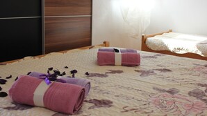 A hotel room with a large bed, two rolled towels, and a floral-patterned bedspread. - Apartments San Paaulo (Dugi Rat)