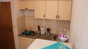 A small kitchen with light-colored cabinets, a countertop, and basic appliances. - Apartments San Paaulo (Dugi Rat)