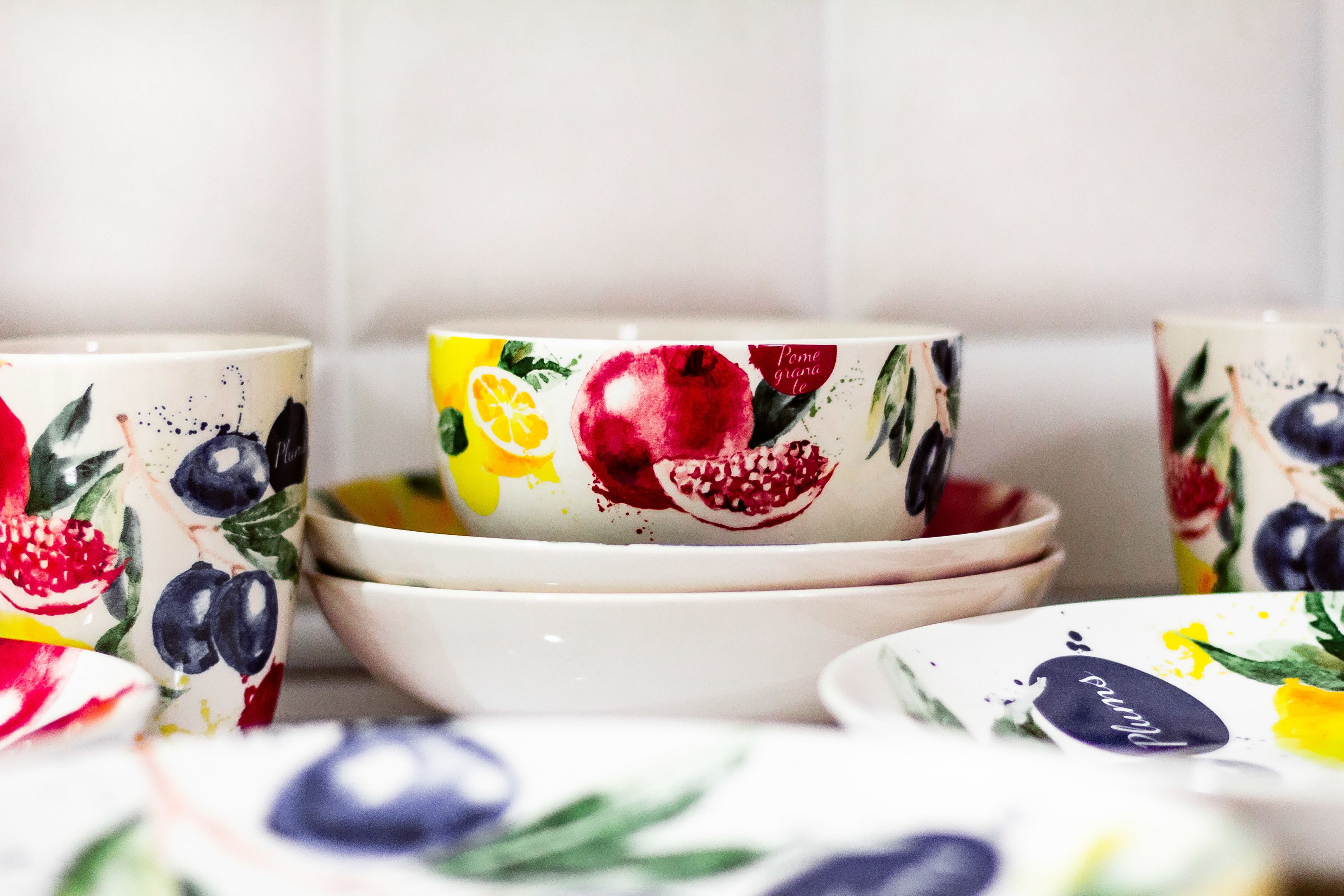 A set of white ceramic bowls with colorful fruit designs.