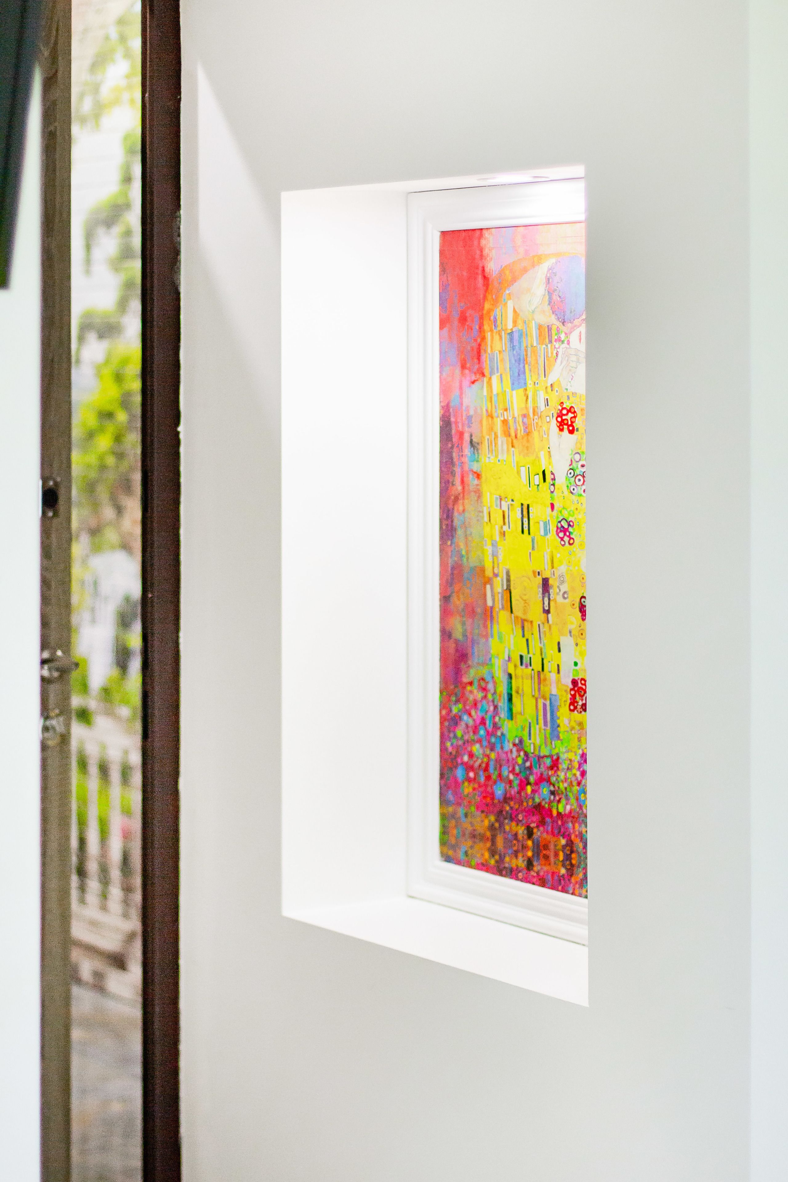A framed artwork in a window, with a view of a building outside.