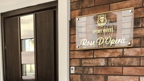 Entrada de un hotel con una puerta de madera oscura, un muro de ladrillo y un letrero que dice "APART HOTEL Rose D'Opéra".