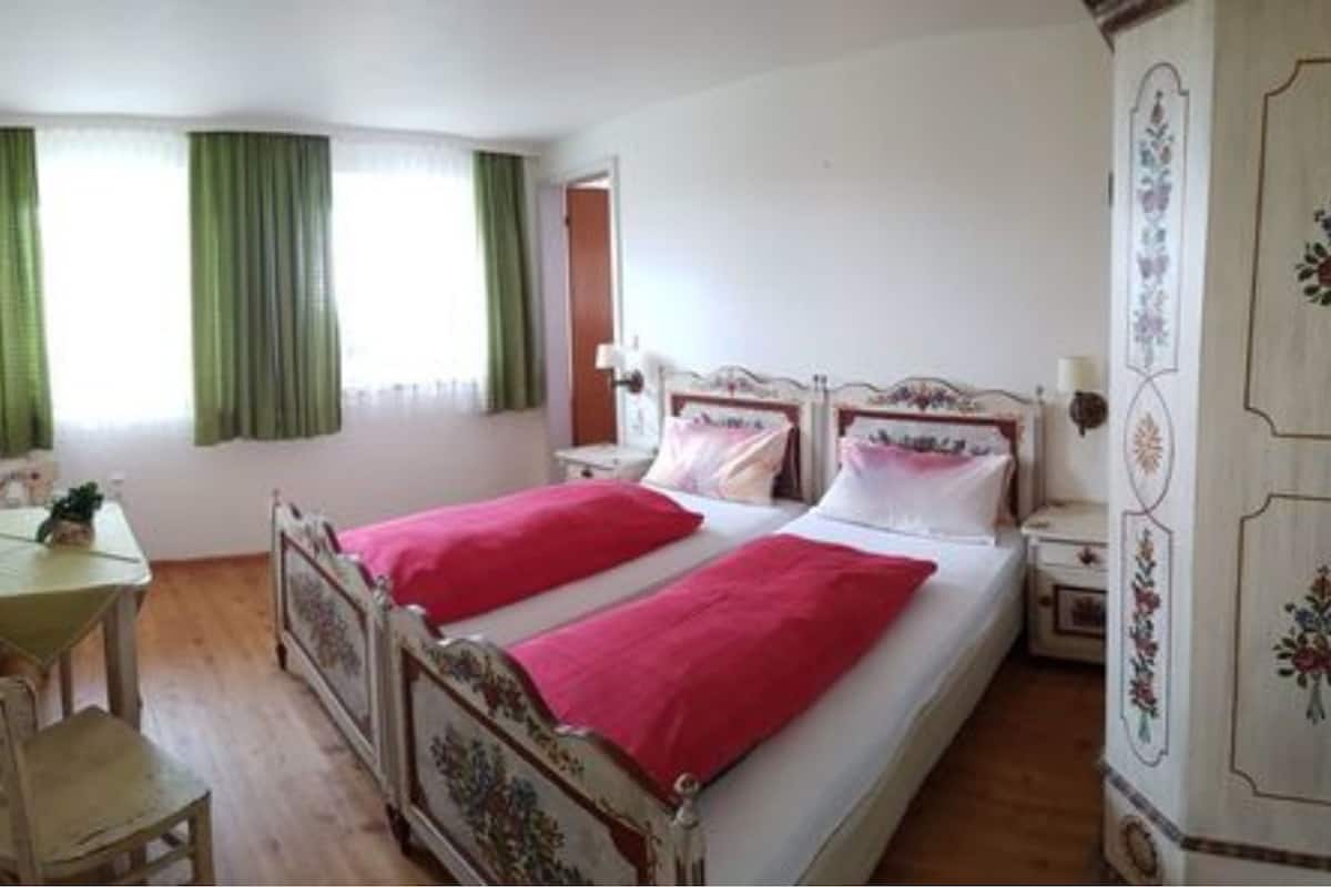 A bedroom with two beds, a wooden desk, and a chair.