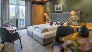 Een hotelkamer met een bed, twee nachtkastjes, een stoel, een klein tafeltje en uitzicht op het landschap.